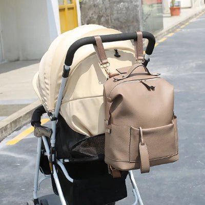 sac a dos a langer marron accroché poussette